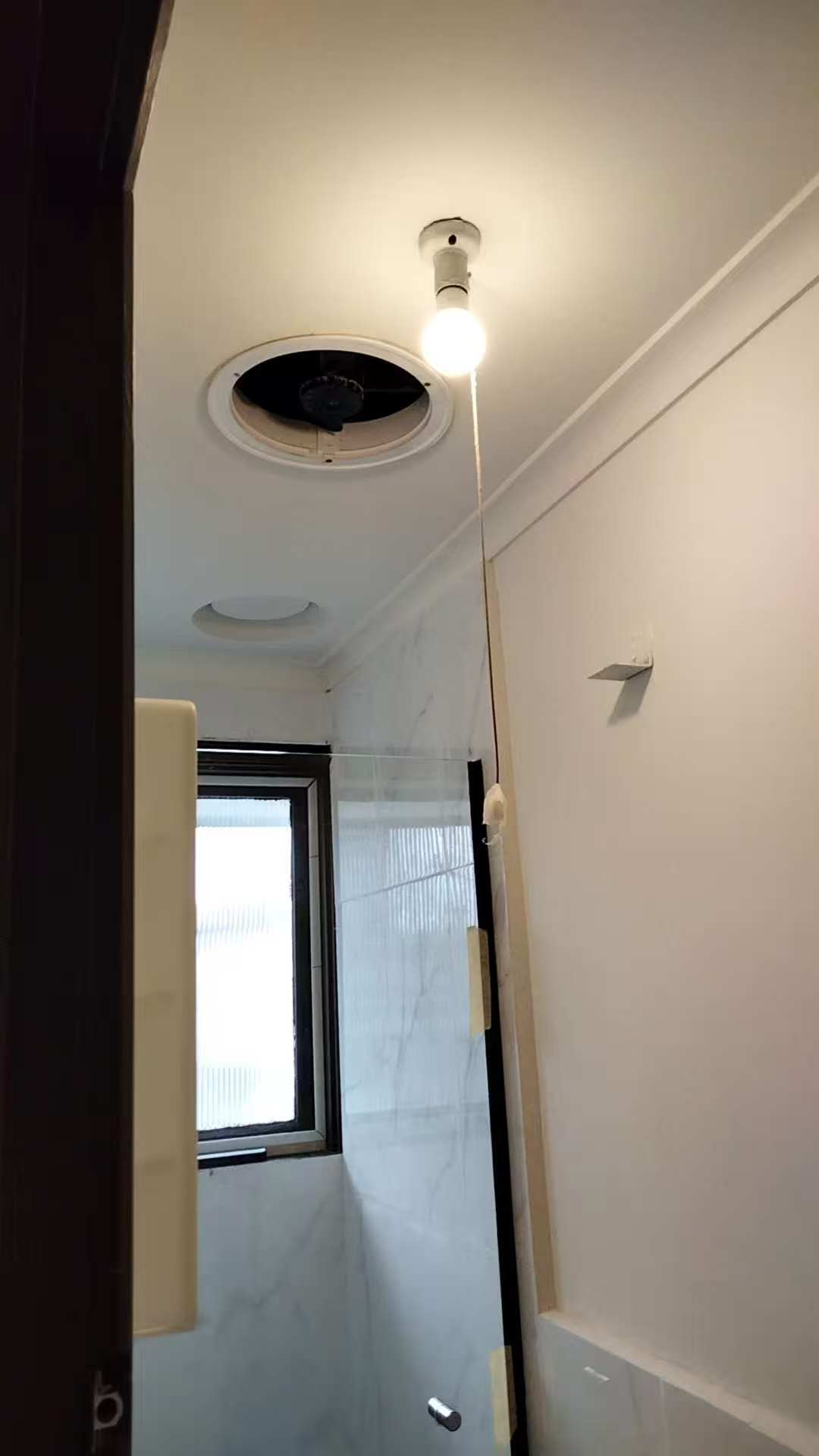 Wide room view with a ceiling opening and a temporary hanging light